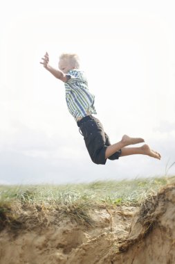 genç çocuk bir kumul atlama.