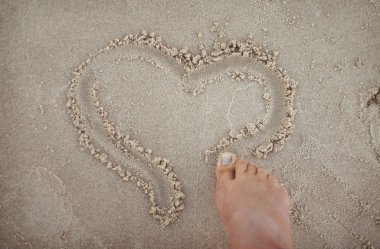 Drawing a heart shape in the sand.