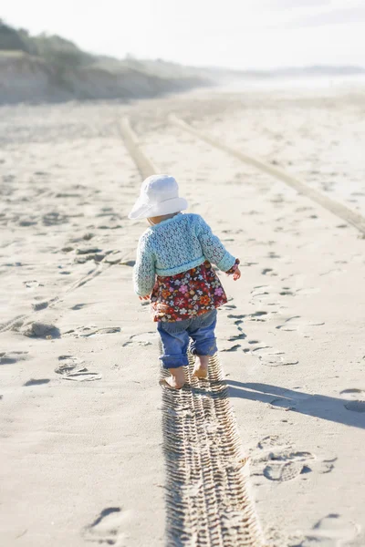 Little girl walking along a tire track o — Stock Photo, Image