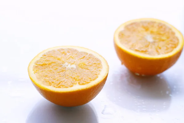 Dos mitades naranjas sobre una superficie clara . — Foto de Stock
