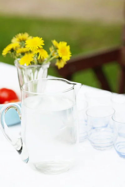 Jarro de água e copos em uma mesa . — Fotografia de Stock