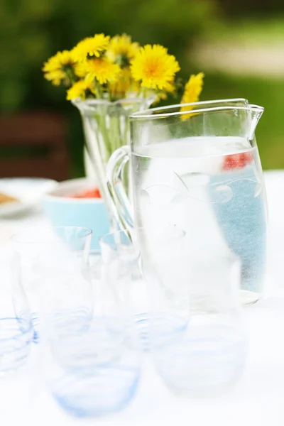 Dzbanek wody i okulary na stole. — Zdjęcie stockowe