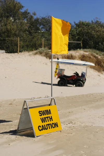 stock image Swimming caution sign and flag on beach.