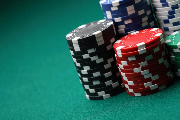 Pilhas de fichas de poker numa superfície verde — Fotografia de Stock