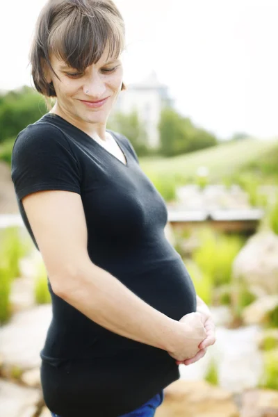 Happy pregnant woman holding her belly w — Stock Photo, Image