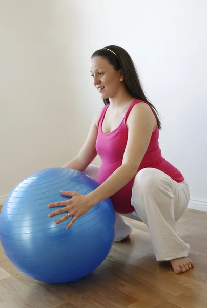 Mladý usmívající se těhotná žena dělá squatu — Stock fotografie