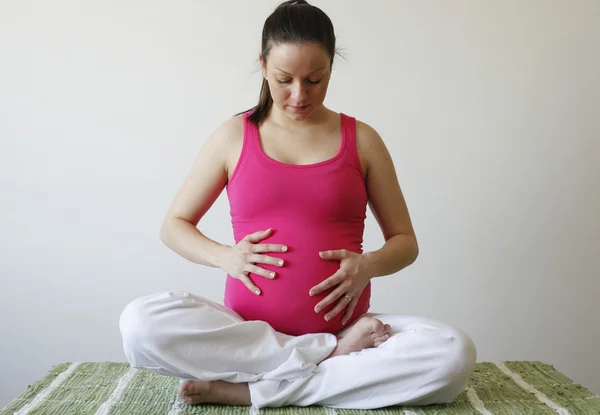 Молодая заботливая беременная женщина держит — стоковое фото