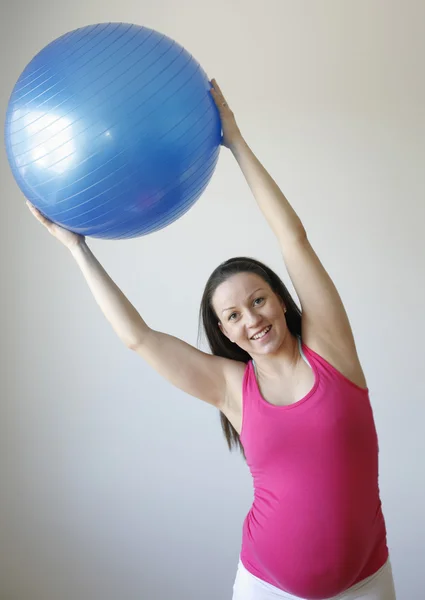 Молодая улыбающаяся беременная женщина занимается спортом — стоковое фото