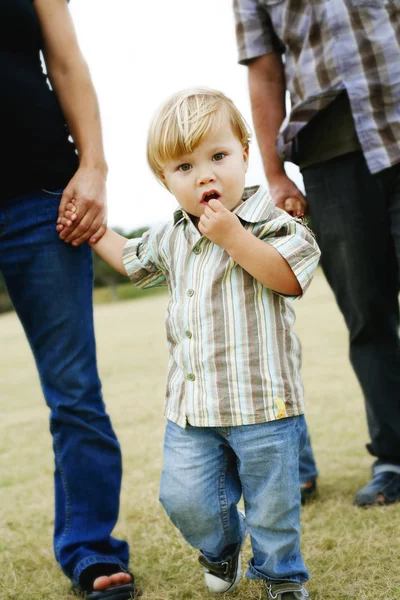 Niño caminando con sus padres en un parque . — Foto de Stock