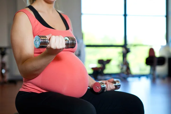 Femme enceinte s'exerçant avec des poids — Photo