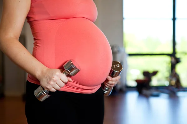 Mujer embarazada sosteniendo pesas —  Fotos de Stock