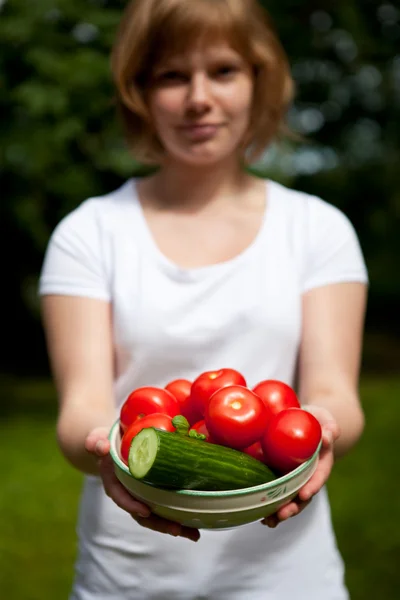 Девушка держит миску помидоров и огурцов — стоковое фото