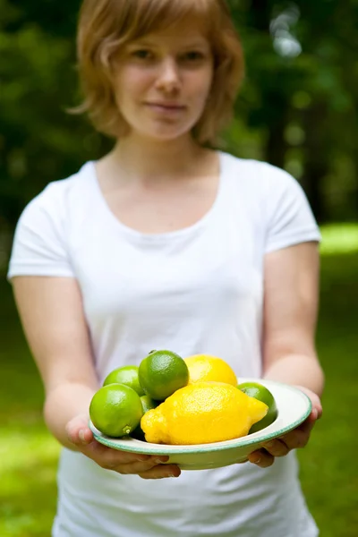 Menina segurando uma tigela de limão e limão — Fotografia de Stock