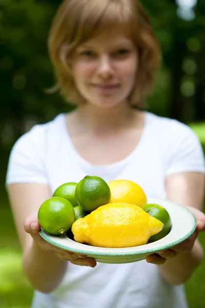 少女抱著一碗的柠檬和酸橙 — 图库照片
