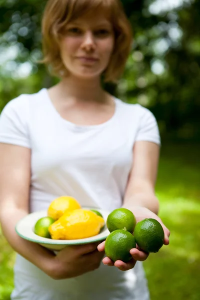 Girl holding a bowl of lemon and lime — Stock Photo, Image