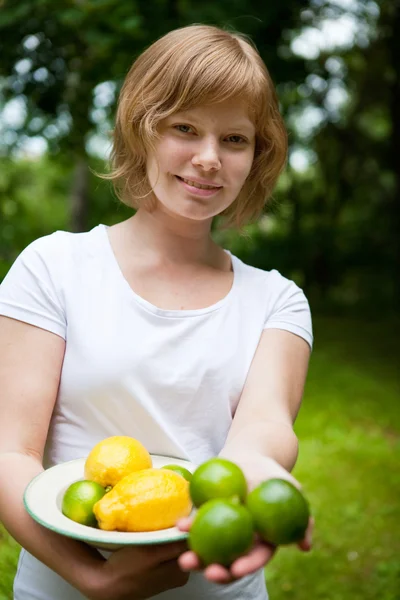 Girl holding a bowl of lemon and lime — Stock Photo, Image
