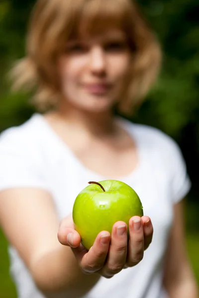 Девушка держит свежее зеленое яблоко — стоковое фото