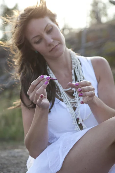 Attraktive Frau trägt im Freien Nagellack auf. — Stockfoto
