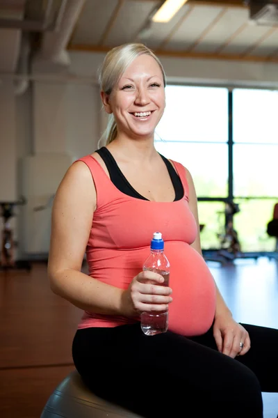 Pregnant woman relaxing with water bottle in hand. — Stock Photo, Image