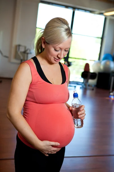 Donna incinta rilassante mentre tiene in mano la bottiglia d'acqua . — Foto Stock
