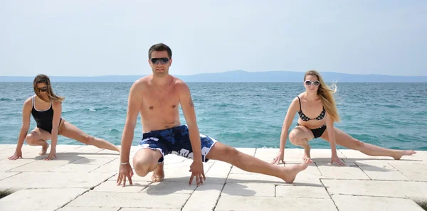 Jóvenes estudiantes practicando yoga en la playa —  Fotos de Stock