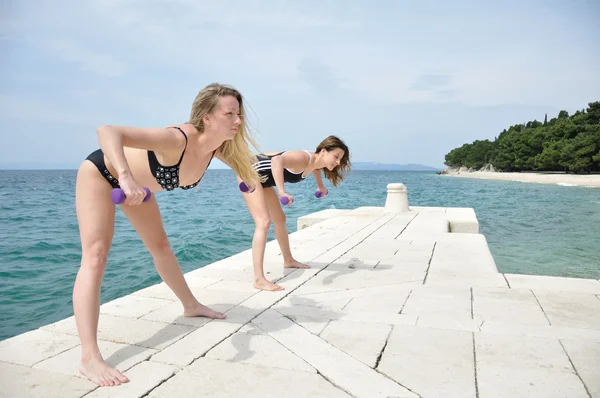 Young students lifting weights on the beach — Stock Photo, Image