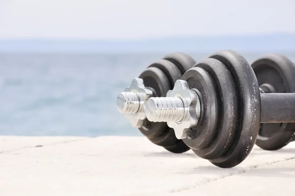 Dumb bells on the beach — Stock Photo, Image
