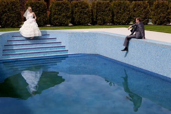 Bruid en bruidegom bij het zwembad — Stockfoto