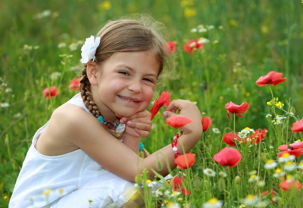 Girl holding a wild poppy in a meadow — Stock Photo, Image