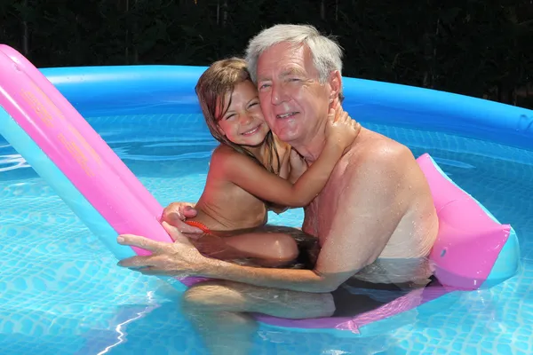 Granddaughter and grandfather cuddling on a lilo — Stock Photo, Image