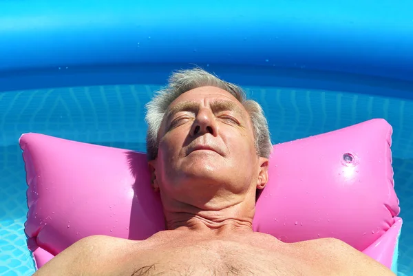 Older man sunbathing in pool — Stock Photo, Image