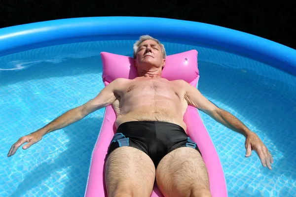 Older man sunbathing in pool Royalty Free Stock Photos