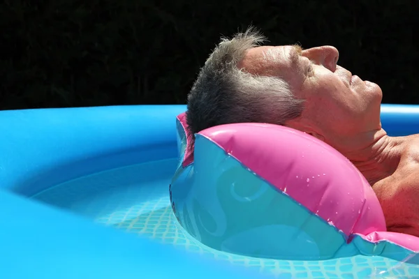 Hombre mayor tomando el sol en la piscina Fotos de stock libres de derechos