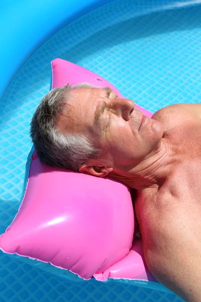 Older man sunbathing in pool Stock Photo