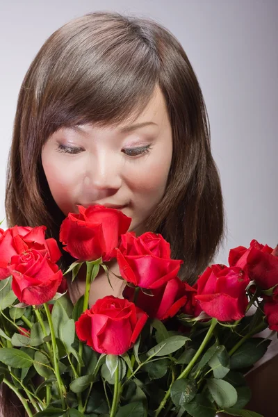 Beautiful asian woman smelling flowers — Stock Photo, Image