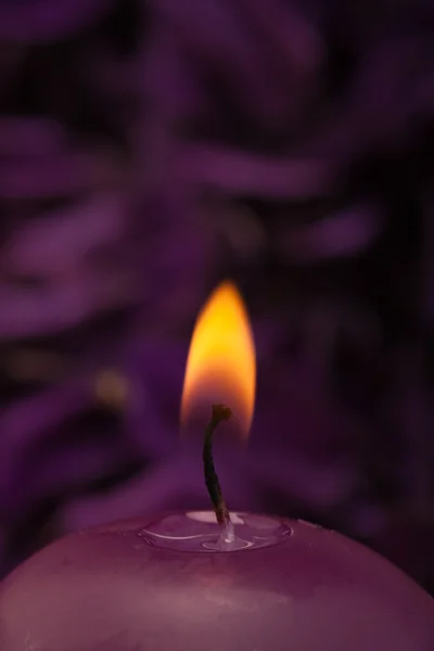 Brennende Kerze mit lila Hintergrund — Stockfoto