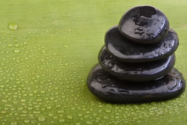 Мокрі гарячі камені на зеленому банановому листі — стокове фото
