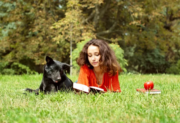 The girl and dog lying on a grass in park — Stock Photo, Image