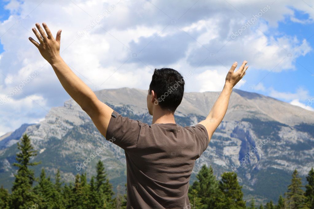 Man standing in nature with arms lifted up