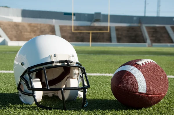 Futebol americano e capacete em campo — Fotografia de Stock
