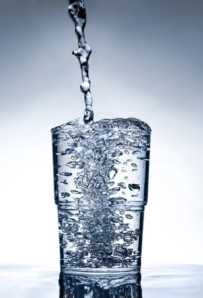 Nette glas staande op water met vloeistof — Stockfoto