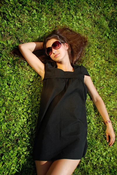 Очаровательная дама в черном платье лежит на траве . Лицензионные Стоковые Изображения
