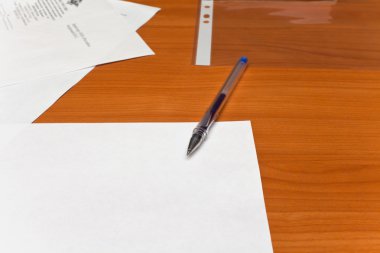 bir masanın üzerinde bir beyaz kağıt kalem