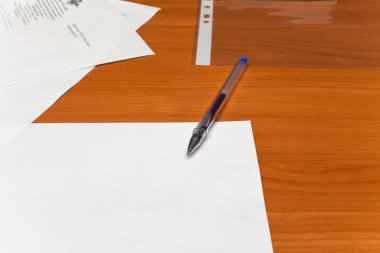 Pen lying on a table, a sheet of white paper clipart