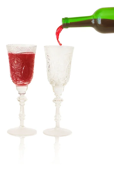 Červené víno stéká ze láhev vína do prázdné sklenice — Stock fotografie