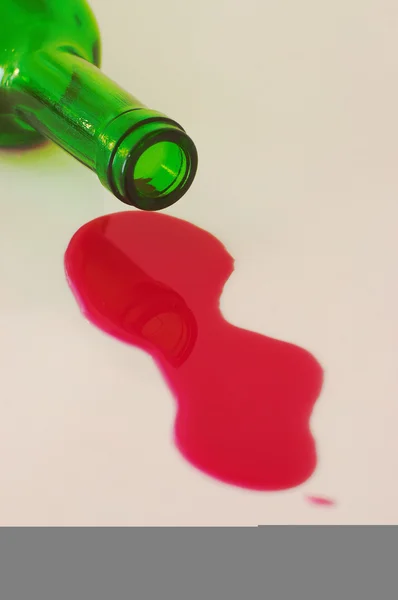 stock image Red wine spilled from green bottle