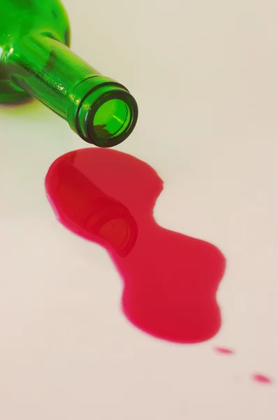 stock image Red wine spilled from green bottle