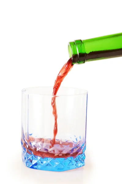 Κόκκινο κρασί, ρίχνει κάτω από ένα μπουκάλι κρασί στο μπλε γυαλί — Φωτογραφία Αρχείου