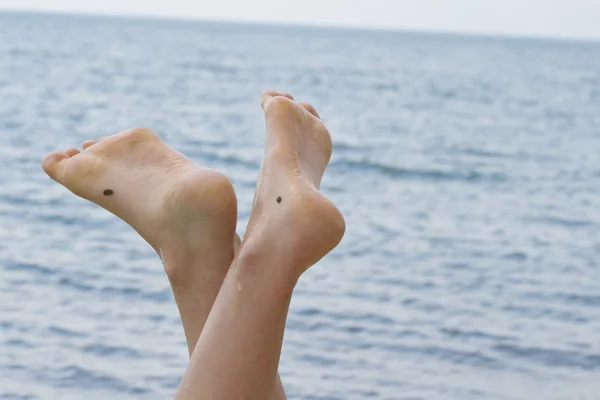 Piedi femminili con il mare sullo sfondo — Foto Stock