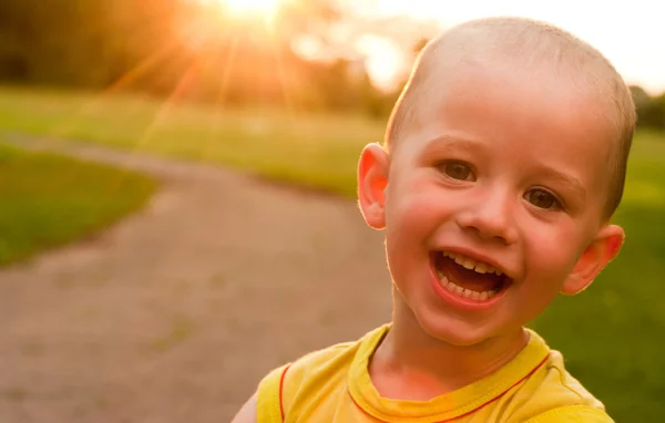 Chlapec s úsměvem ve fotoaparátu při západu slunce pozadí — Stock fotografie
